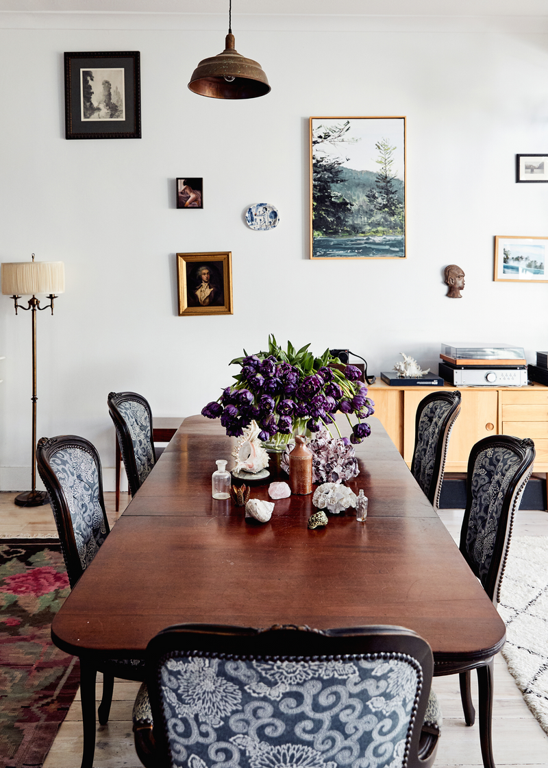 Grandmillennial style dining room with a wooden table, artwork and patterned chairs