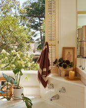 Bathroom with plants, and a window view of trees with the cotton terry two-toned towel in creme and cacao hand towel. - view