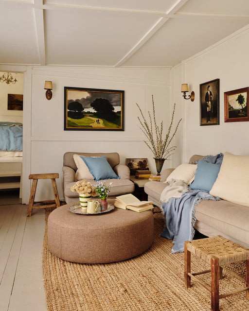 Living room with beige sofa and ottoman, and cushions and throws in lagoon and cream.