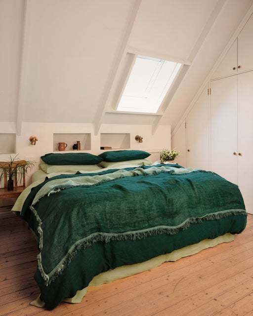 Bedroom with green bedding and a skylight.