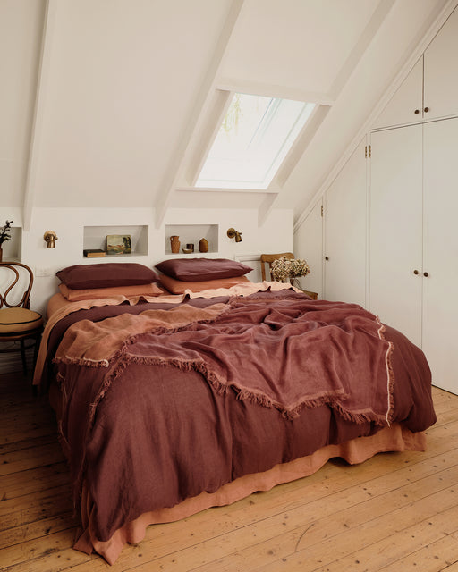 Bedroom with wooden floor, bed with brown bedding, and skylight.