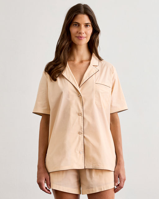 A woman with long brown hair wears the Bed Threads Vanilla & Espresso Piped Short Sleeve Shirt, a lightweight cotton set with contrast piping, standing against a plain light background and smiling slightly.