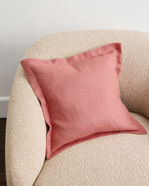An Oatmeal 100% French Flax Linen Cushion Cover by Bed Threads is arranged neatly on a wooden stool, set against a plain white wall.