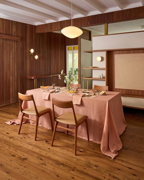 A modern dining room features wood paneling, minimalist decor, and a rectangular table for four topped with the Hazelnut & Terracotta 100% French Flax Linen Table Bundle by Bed Threads, Classic Placemats, and two wooden chairs.