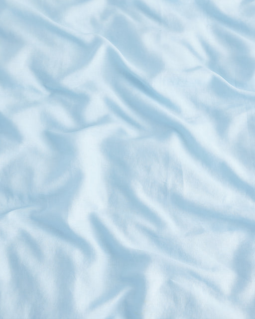 The Coast 100% French Flax Linen Duvet Cover Set by Bed Threads features a light blue fabric with gentle, soft wrinkles and folds, providing a smooth, textured look ideal for luxurious bedding.