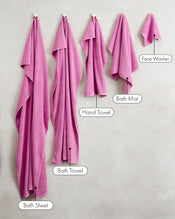 Five Bubblegum 100% Cotton Terry towels by Bed Threads—Bath Sheet (largest), Bath Towel, Hand Towel, Bath Mat, and Face Washer—hang neatly on the wall. Enjoy plush, quick-drying luxury for your bathroom. - view