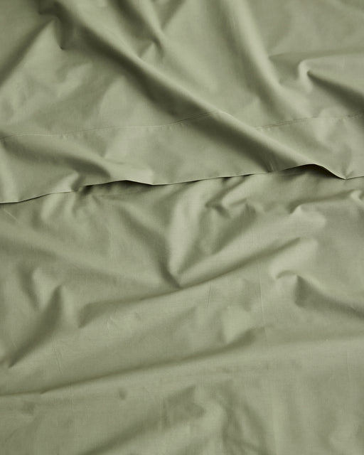 A close-up of olive green fabric with soft folds and a horizontal seam, filling the entire frame.