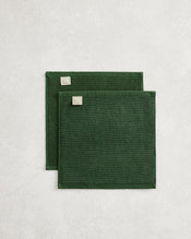 Set of two Moss 100% Cotton Terry Face Washers by Bed Threads, dark green with stitched edges and small corner labels, displayed on a light textured surface. Soft, absorbent, and ideal for daily facial care. - view
