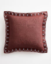 The Bed Threads Cacao & Coast 100% French Flax Linen Swirl Cushion Cover is a square maroon design with decorative white swirl edges, shown against a white background. - view