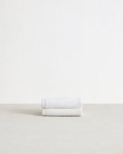 The Bed Threads Crisp White 100% Cotton Terry Face Washers (Set of Two) are stacked on a light surface against a plain white background—soft, absorbent, and gentle on skin. - view