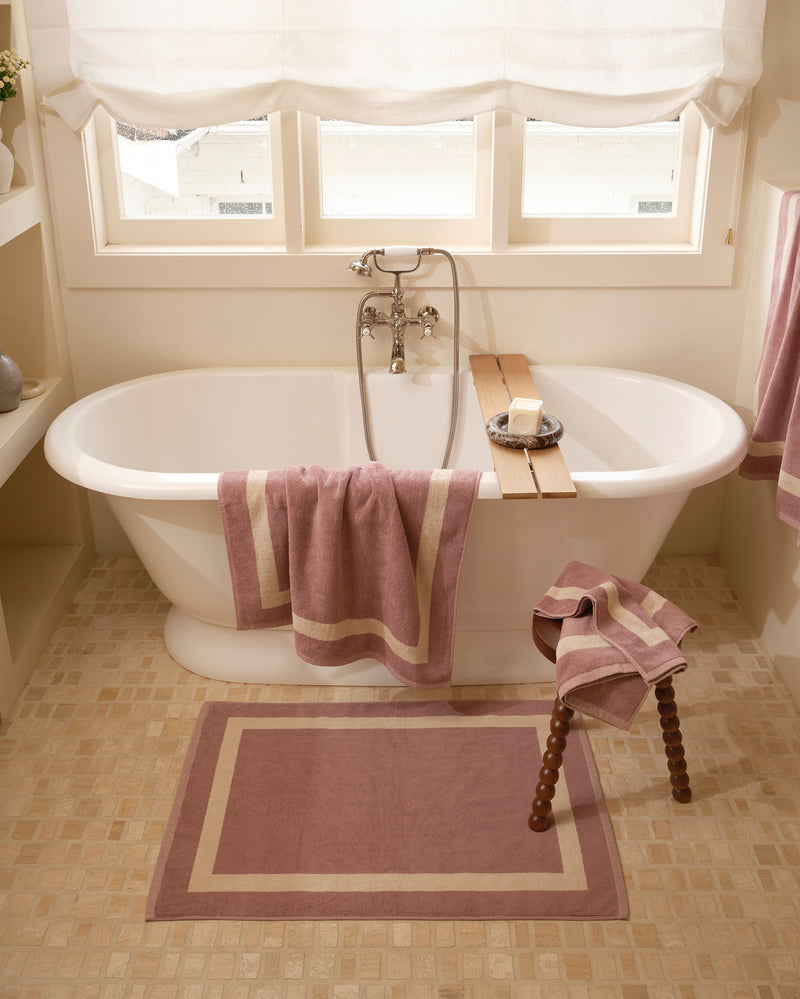 Close up of a freestanding bath tub with cotton terry towels in a lavender colour with creme border.