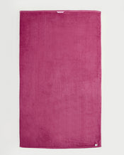 A large, rectangular magenta Berry 100% Cotton Terry Bath Sheet by Bed Threads is laid flat on a white background. The plush towel has a soft texture and features a small white label on one corner. - view