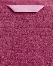 A close-up of the Bed Threads Berry 100% Cotton Terry Bath Sheet, featuring a plush pink texture and a handy folded fabric loop—ideal for those seeking quick-drying comfort. - view