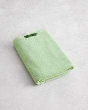 A neatly folded Apple 100% Cotton Terry Bath Towel by Bed Threads rests on a light, textured surface, highlighting its plush 650GSM softness. - view