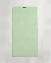 A set of two Apple 100% Cotton Terry Bath Towels by Bed Threads, in light green, lies flat on a white surface, each featuring a small fabric tag in the corner and a hanging loop at the top edge. - view