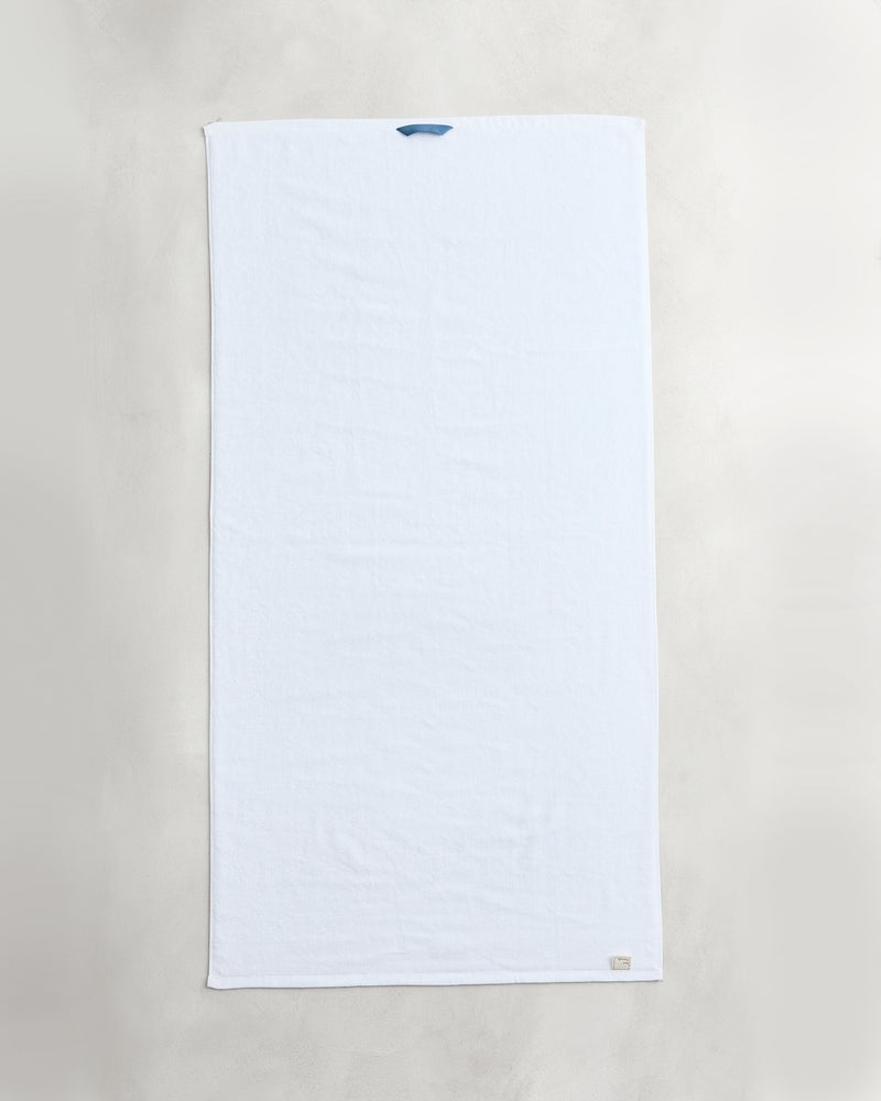 A set of two Bed Threads Crisp White 100% Cotton Terry Bath Towels is laid flat on a light surface, featuring a small blue loop and beige tag, highlighting their plushness and high absorbency.
