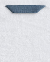 A close-up of Bed Threads’ Crisp White 100% Cotton Terry Bath Towels (Set of Two), featuring a blue fabric loop sewn near the top edge for easy hanging. - view