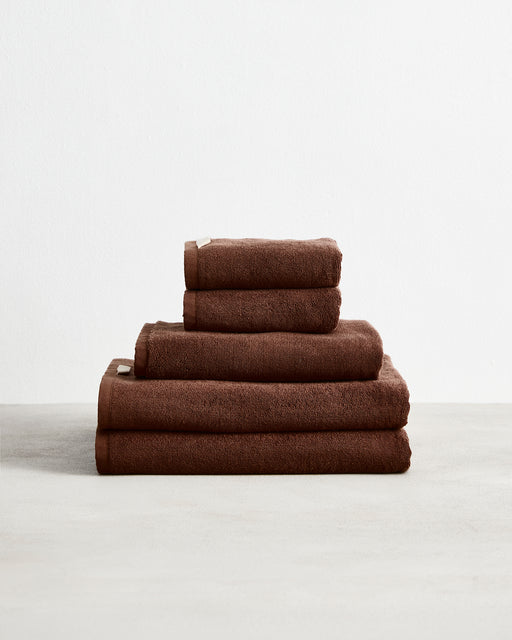 The Bed Threads Espresso 100% Cotton Terry Bath Towel Bundle, featuring neatly stacked towels in various sizes, is displayed on a light surface against a plain white background.