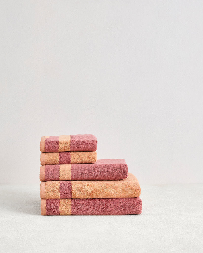 The Bed Threads Terracotta & Pink Clay Two-Toned 100% Cotton Terry Bath Towel Bundle features five folded towels in warm pink tones with stripes, neatly arranged against a plain light background.