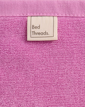A close-up of Bubblegum 100% Cotton Terry Face Washers by Bed Threads, featuring a beige Bed Threads label and crafted from soft, absorbent terry that's gentle on skin—perfect for daily cleansing. Set includes two face washers. - view