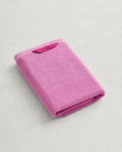 The Bed Threads Bubblegum 100% Cotton Terry Hand Towel, featuring plush 650GSM fabric, is neatly folded on a light textured surface, highlighting its ultimate softness, quick-drying convenience, and small fabric tag. - view