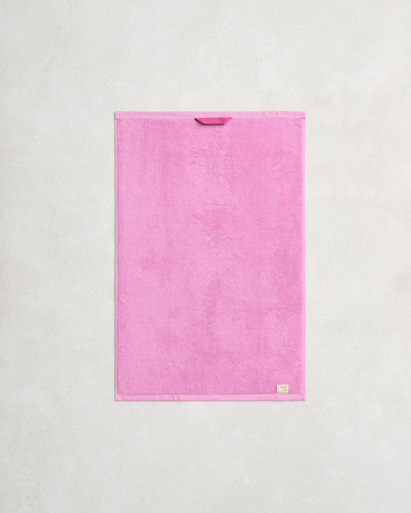 The Bubblegum 100% Cotton Terry Hand Towel by Bed Threads is a bright pink, rectangular, quick-drying 650GSM towel with a fabric loop and beige tag for easy hanging and added style.