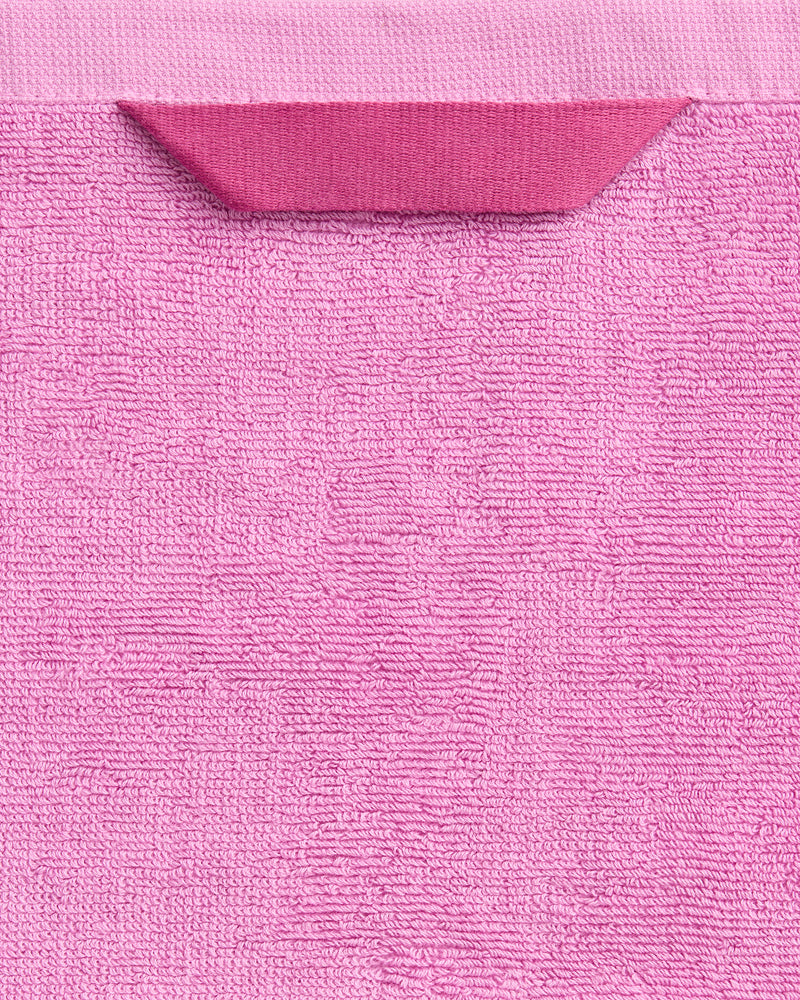 A close-up of the Bubblegum 100% Cotton Terry Bath Sheet by Bed Threads, featuring a folded pink corner and contrasting band—an ultra-soft, quick-drying towel that adds comfort and style to your luxury bathroom collection.