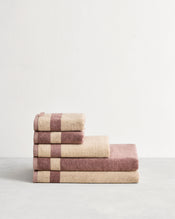 Stack of cotton terry bath towels in reversible colours creme and lavender.  - view