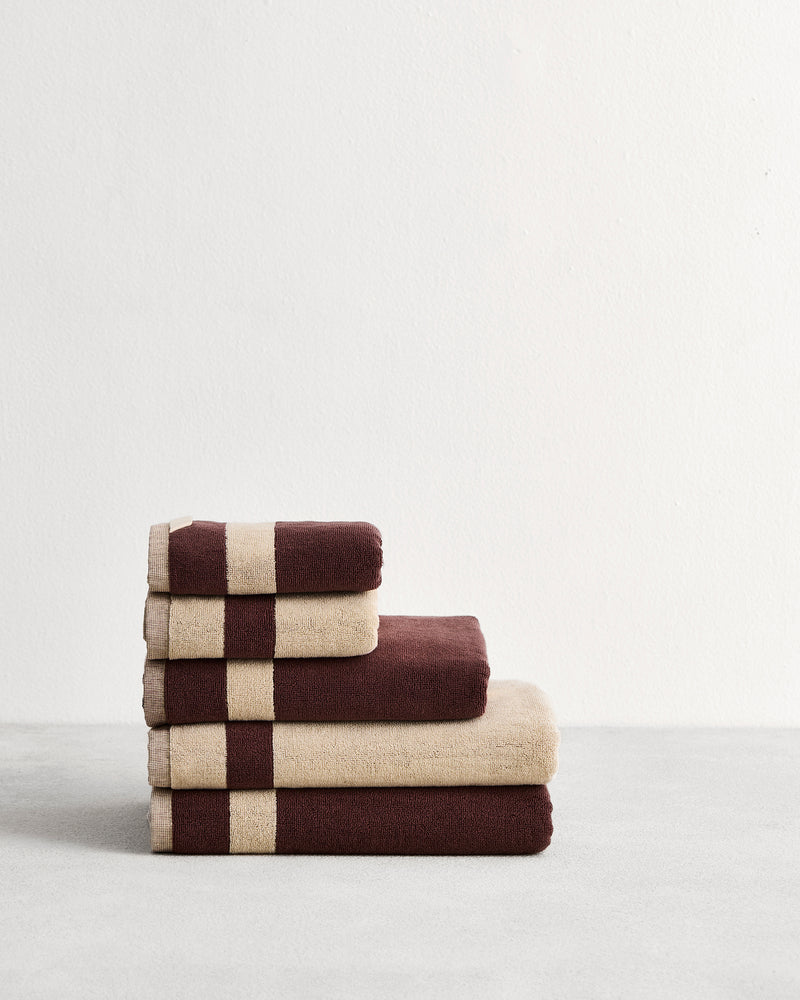 Stack of cotton terry bath towels in reversible colours creme and cacao. 