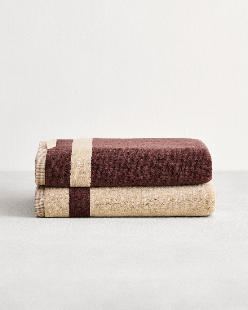 Stack of two cotton terry bath towels in reversible colours creme and cacao. 