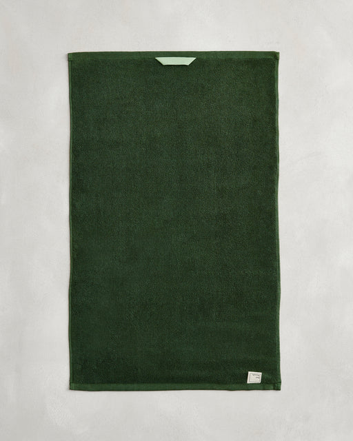 A set of two Moss 100% Cotton Terry Hand Towels by Bed Threads is shown flat on a light gray surface, featuring a small light green loop near one edge and a white label in one corner.