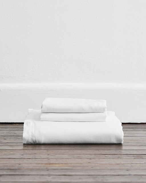 The Bed Threads White 100% French Flax Linen Duvet Cover Set, shown neatly folded against a white wall, is perfect for pairing with matching pillowcases or elevating your bedding ensemble.