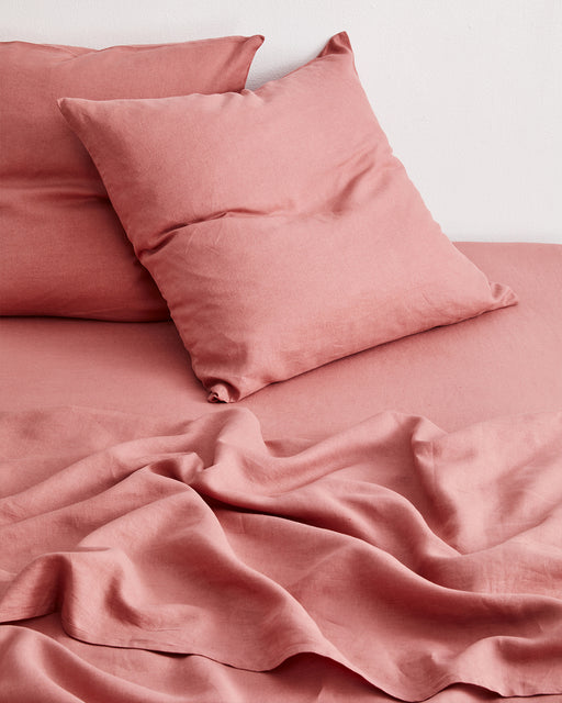 Two Pink Clay 100% French Flax Linen European Pillowcases by Bed Threads rest on a matching bed, their soft linen and gentle wrinkles creating a cozy and inviting look.