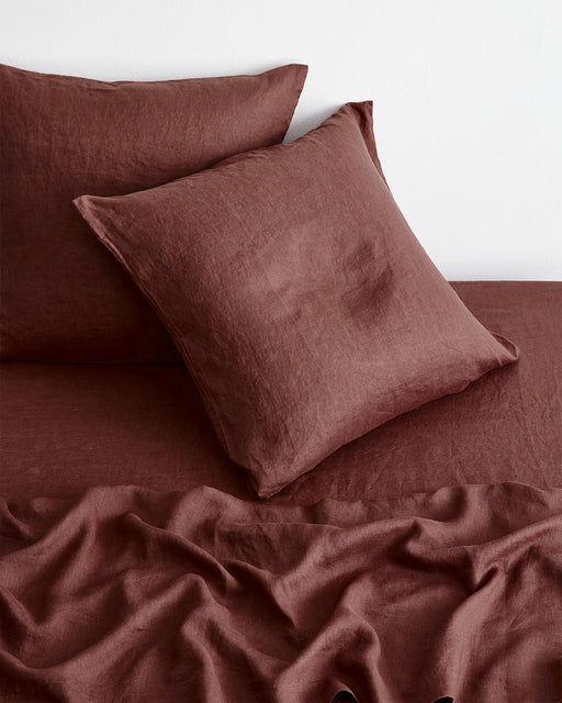 The bed features Bed Threads’ Cacao 100% French Flax Linen European Pillowcases (Set of Two), with a square pillow in front, another behind it, and a relaxed sheet draped over the mattress.