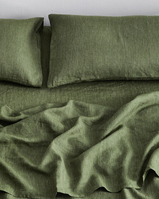 The Bed Threads Olive Stripe 100% French Flax Linen Fitted Sheet, shown on a bed with two matching pillowcases, looks soft and inviting with its slightly wrinkled, temperature-regulating linen fabric.